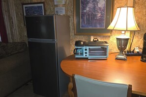 A compact kitchen with a refrigerator, a toaster oven, and a coffee maker on a wooden table. - D1 Dryfork Forest Retreat-electric-heat (Parsons)