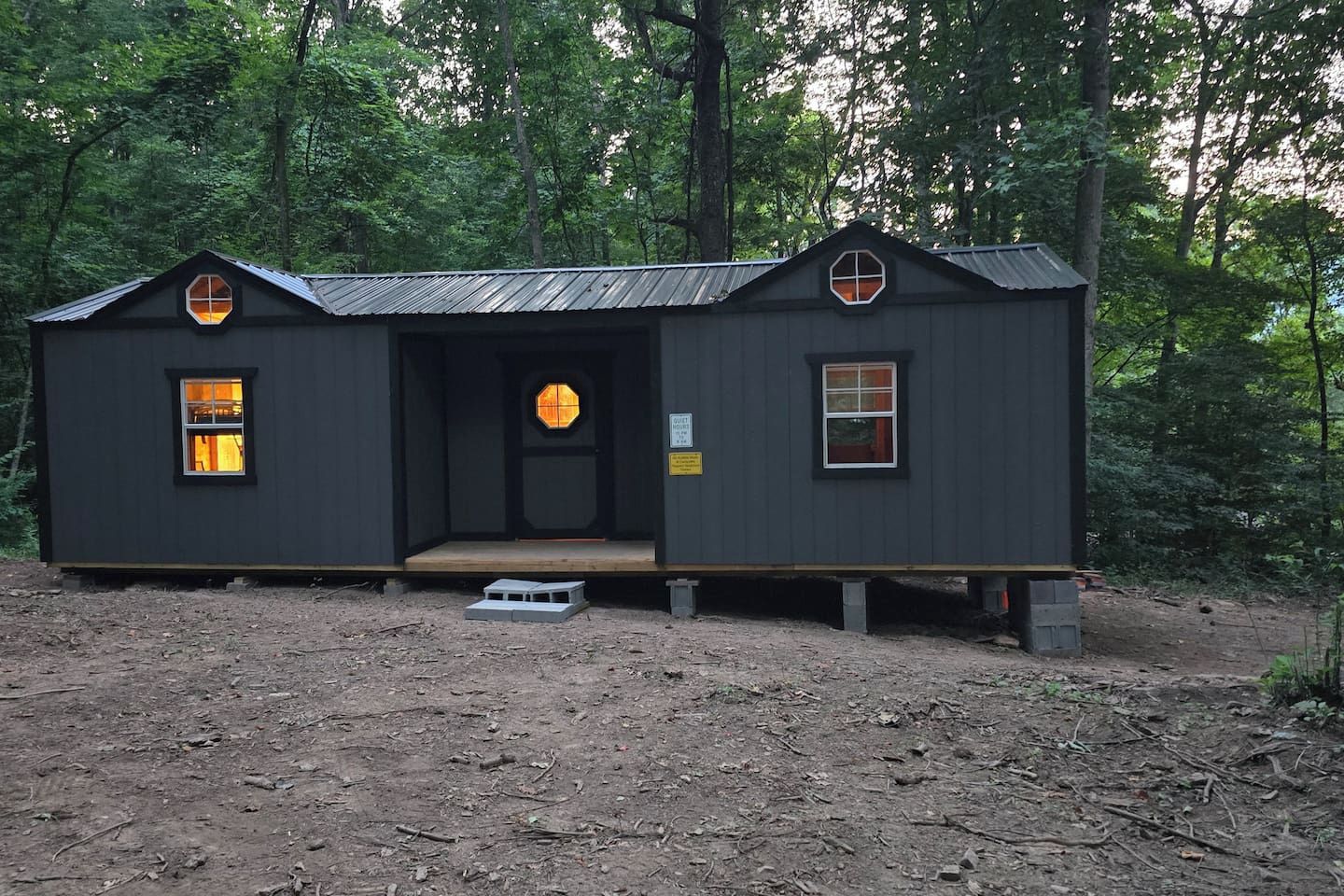 A small cabin with a front porch, a single door, and two windows.