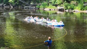 Eine Gruppe von Menschen in Schlauchbooten auf einem Fluss, umgeben von viel Grün.