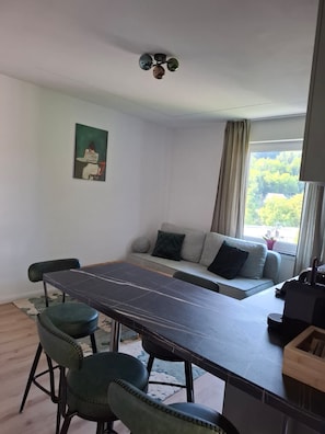 Un ambiente moderno con un tavolo da pranzo, sedie, un divano e una ventola a soffitto.