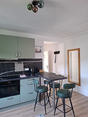 Una cucina moderna con piano di lavoro in marmo, mobili verdi e un'area pranzo con quattro sgabelli.