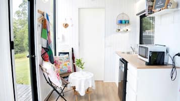 Une cuisine de taille réduite, équipée d’un four à micro-ondes, d’une petite table et d’une chaise.
