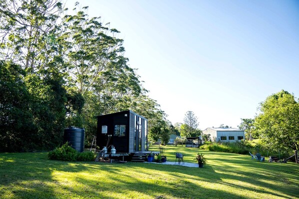 Une maison moderne dotée d’une petite terrasse, entourée d’une pelouse bien entretenue et d’arbres.