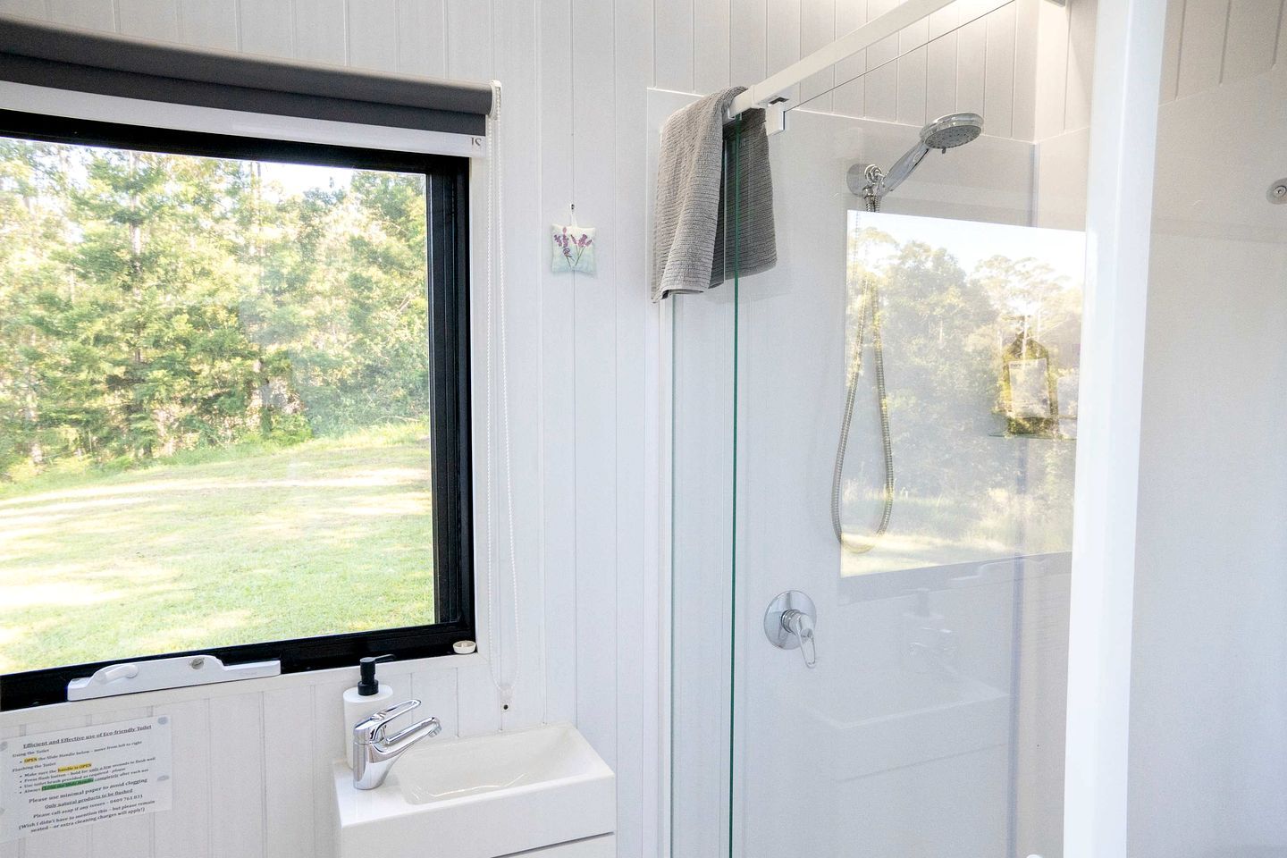 A bathroom with a window, a sink, and a shower.