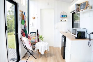 Cocina compacta con microondas, una mesita y una silla.
