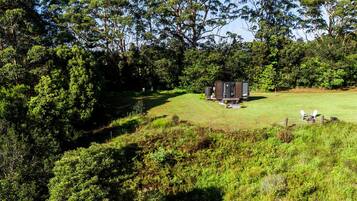 A small cabin with a single room, surrounded by a grassy area and dense trees.