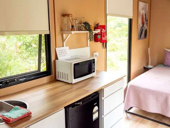 A compact kitchenette with a microwave, a small sink, and a compact dishwasher.
