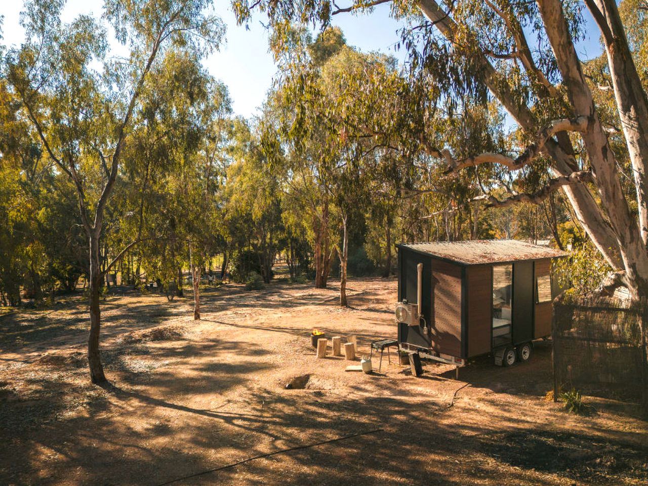 Un camping con una pequeña cabaña de madera, una mesa de picnic y un pozo para fuego.