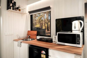 A compact kitchen with a wooden countertop, a microwave, a toaster, and a coffee maker.