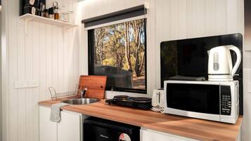 A compact kitchen with a wooden countertop, a microwave, a toaster, and a coffee maker.