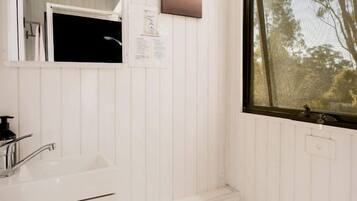 A bathroom with a white sink, a mirror, a window, and a toilet.