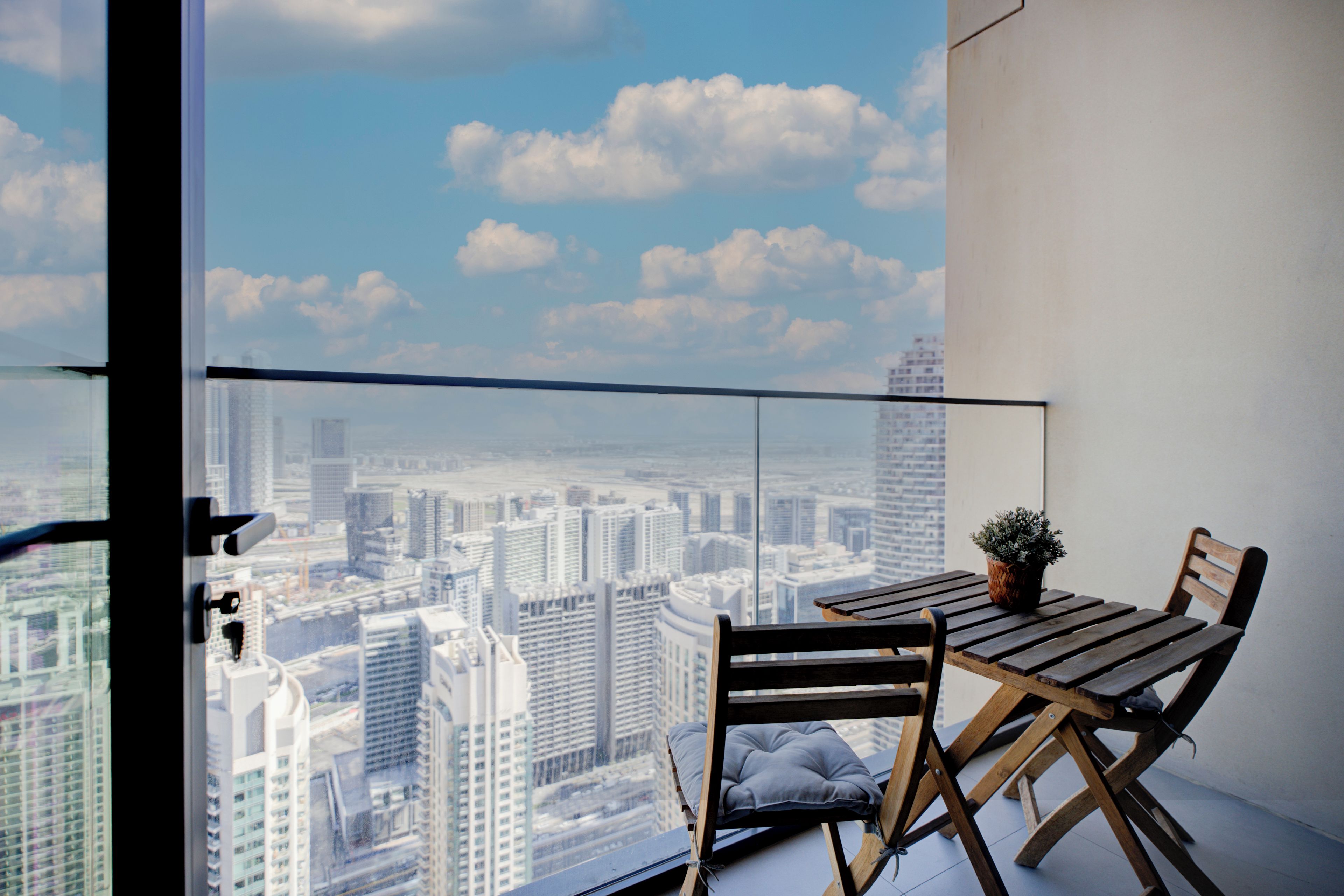 Un balcon avec vue sur la ville, une table, deux chaises et une plante en pot.