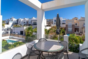 A balcony with a table and chairs, a pool, and a view of surrounding buildings. - Villa in Nerja With Sea Views & Pool (Nerja)