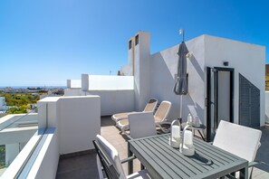 A rooftop terrace with a table and chairs, a small table with candles, and a view of the city. - Villa in Nerja With Sea Views & Pool (Nerja)