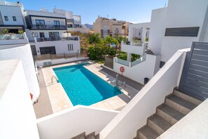 A rooftop swimming pool with a clear blue water, surrounded by modern buildings and a staircase leading to an upper level. - Villa in Nerja With Sea Views & Pool (Nerja)