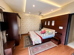 Un dormitorio con cama, televisión, armario y ventilador de techo.