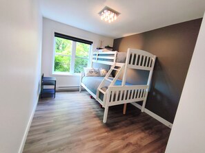 A room with a bunk bed, a desk, and a window with a view of trees. - Luxury Condo with Shuttle Service / 3 Bedrooms, Fully Equipped (Bromont)