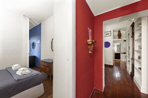 Ein Hotelzimmer mit Bett, Schminktisch, Kommode und einem Flur, der zu einem Badezimmer führt.