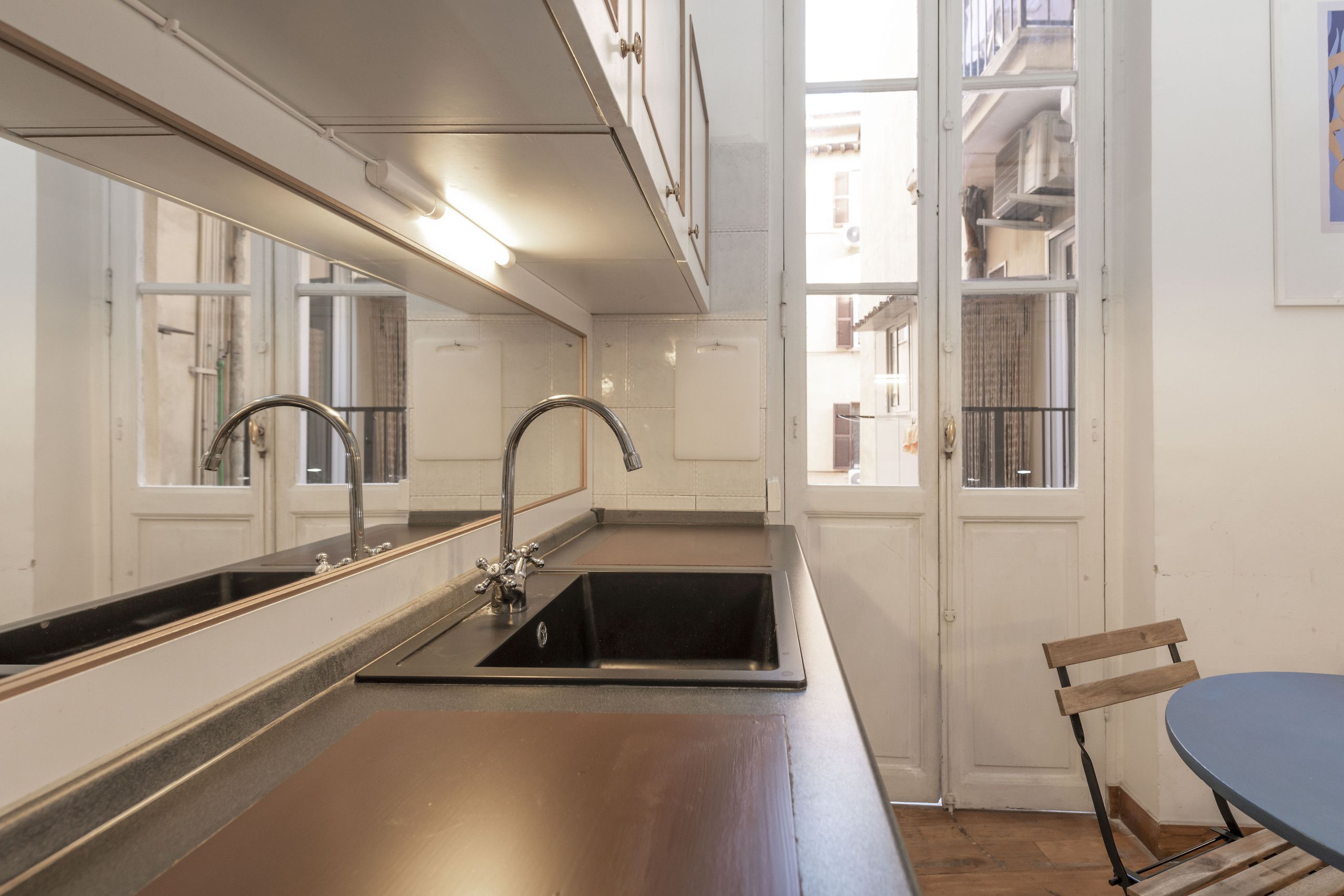 Une cuisine moderne dotée d’une grande fenêtre, d’un évier et d’un coin repas avec une table et une chaise.