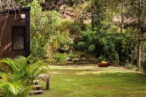 A garden with a wooden structure, a fire pit, and outdoor furniture.