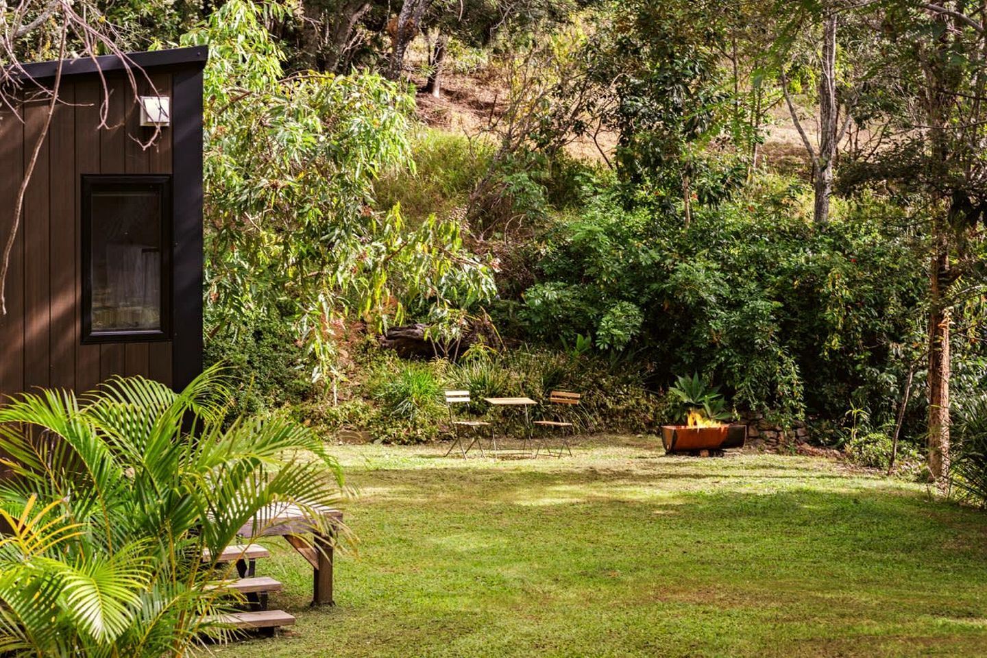 Un jardin agrémenté d’une structure en bois, d’un foyer et de mobilier d’extérieur.