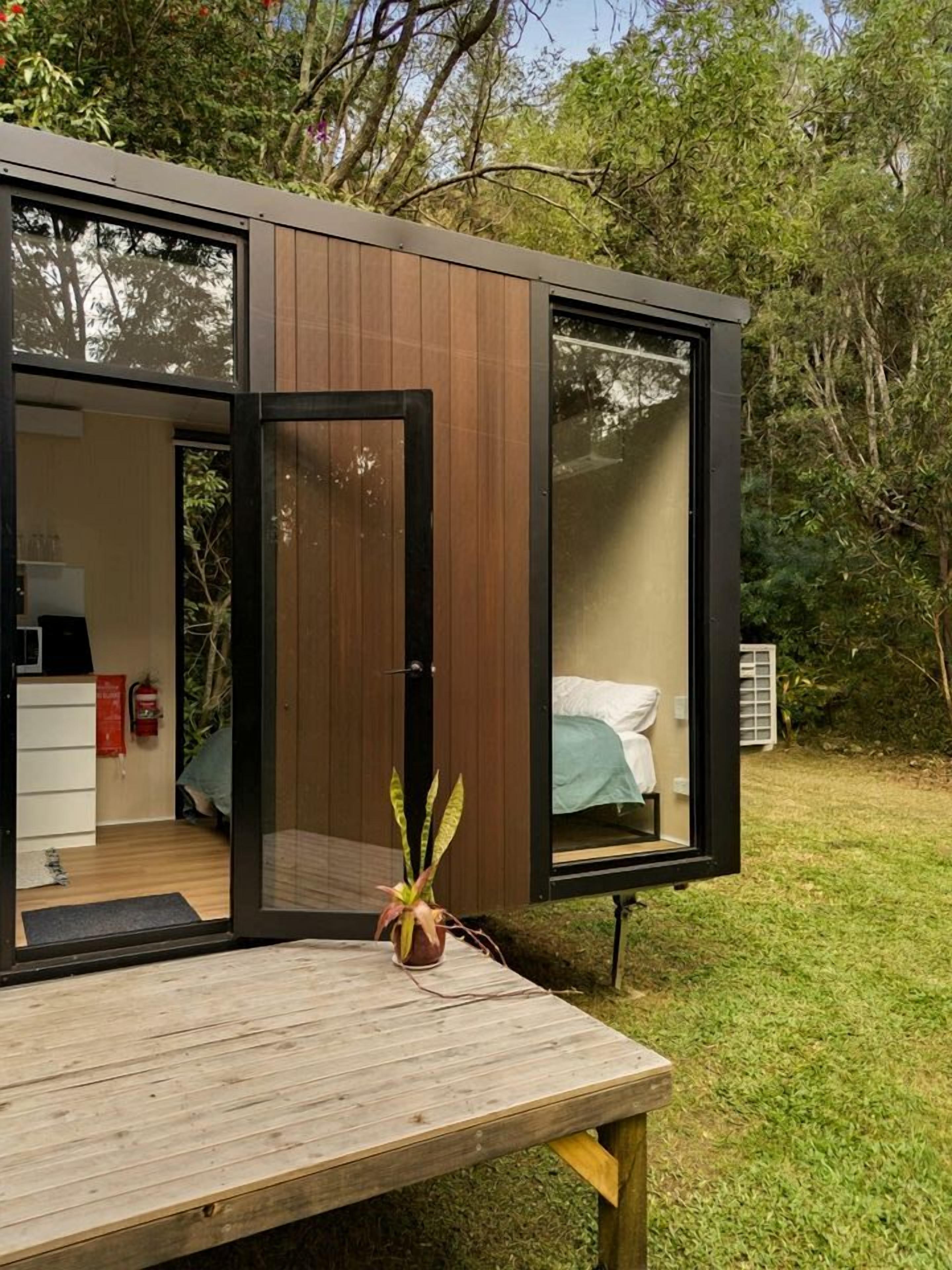 Quarto moderno e espaçoso, com cama, escrivaninha, mesa de madeira e um vaso com planta.