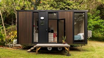 Une maison mobile moderne et compacte, dotée d’un petit porche, d’un lit et d’une kitchenette.