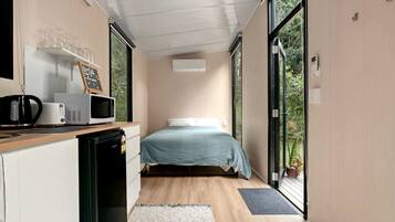 Une chambre avec un lit, un bureau doté d’un micro-ondes et une vue sur la verdure par la fenêtre.