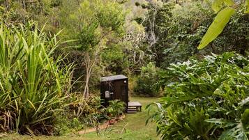 A small wooden structure with a bench in a lush garden setting.