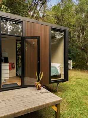 Una habitación moderna de concepto abierto con cama y escritorio, una mesa de madera y una planta en maceta.