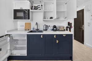 Eine moderne Küche mit eingebauten Geräten, einem dunkelblauen Schrank und einer weißen Arbeitsplatte.