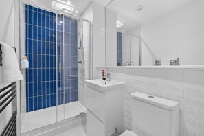 Ein modernes Badezimmer mit einer Duschkabine aus Glas, einem weißen Waschbecken und einem großen Spiegel.