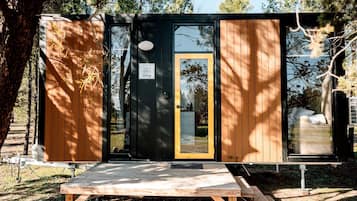 A compact cabin with a door, a small window, and a wooden deck.
