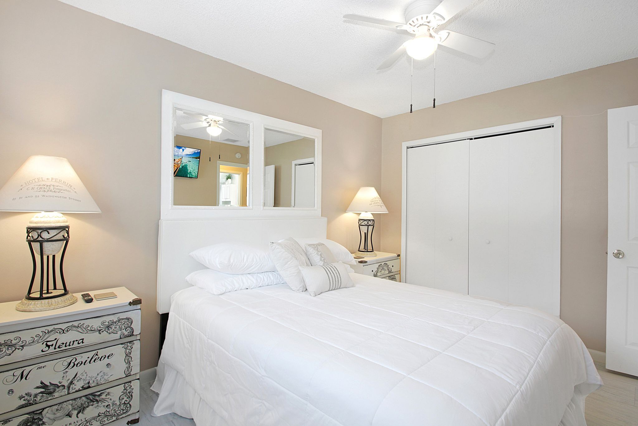 A hotel room with a bed, two bedside tables, a ceiling fan, and a wardrobe.