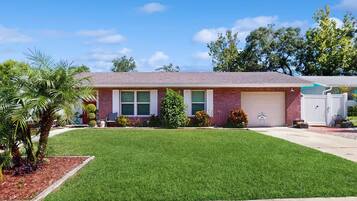A single-story brick house with a front yard, a garage, and a small garden area.