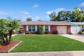 A single-story brick house with a front yard, a garage, and a small garden area.