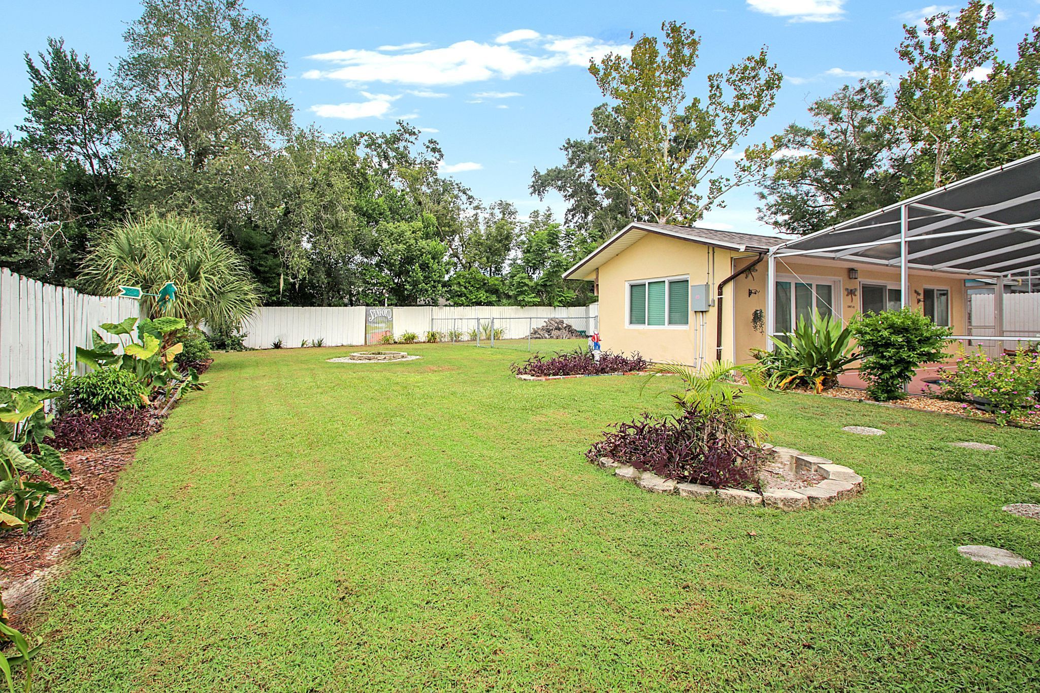 A residential backyard with a well-maintained lawn, a small shed, and a covered patio area.