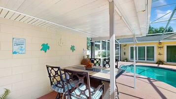 An outdoor patio with a pool, a covered seating area, and a wall with decorative elements.