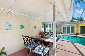 Une terrasse extérieure avec une piscine, un espace salon couvert et un mur agrémenté d’éléments décoratifs.