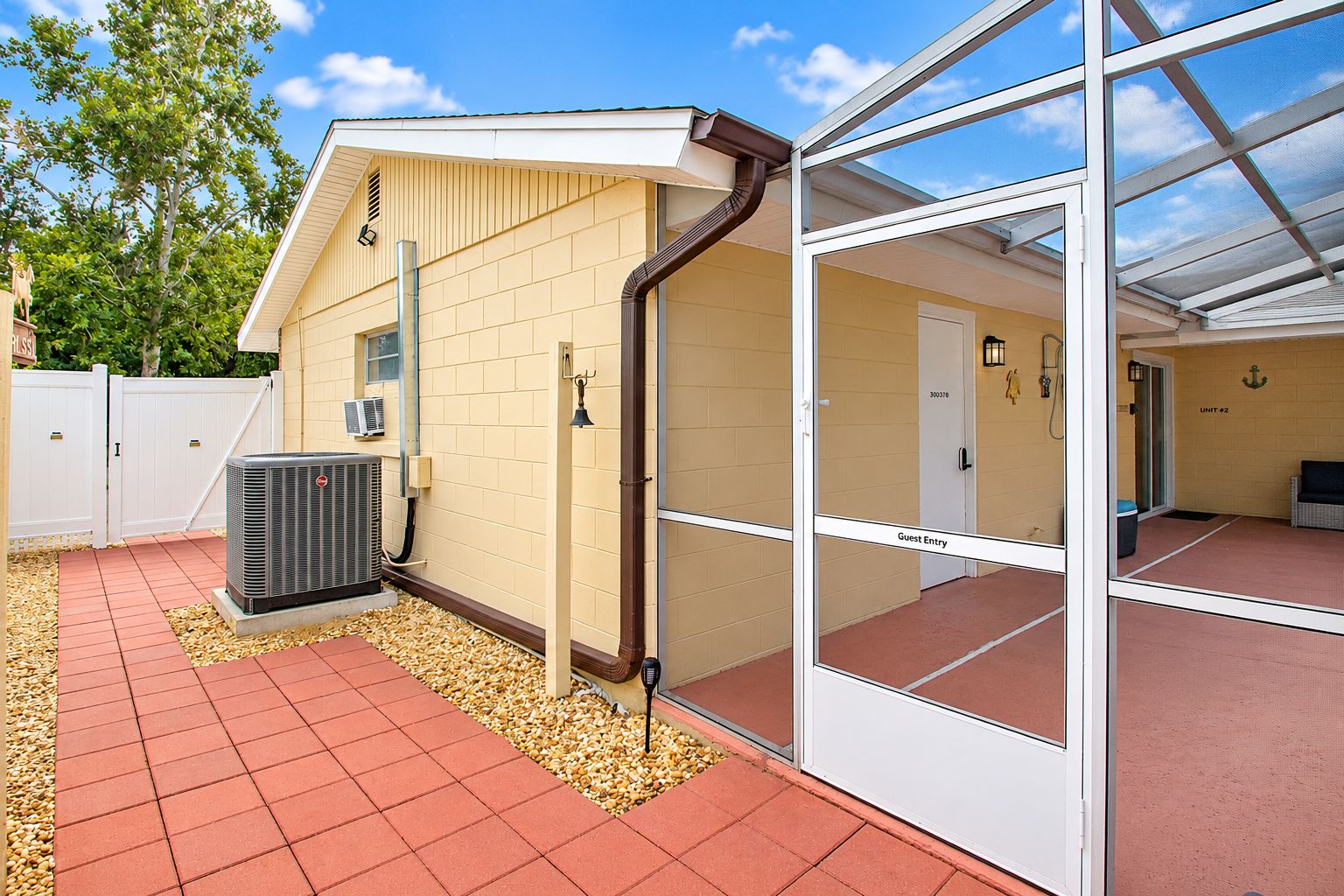 A guest entry area with a glass door, a brick wall, and an air conditioning unit.