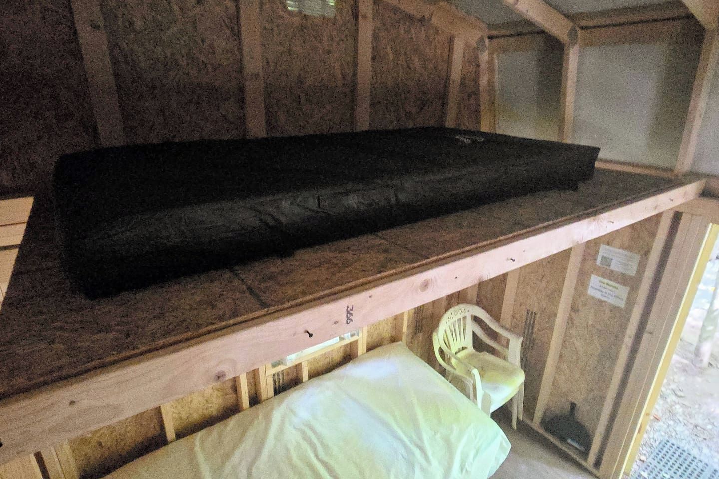 A bunk bed with a mattress on the top bunk and a pillow on the bottom.
