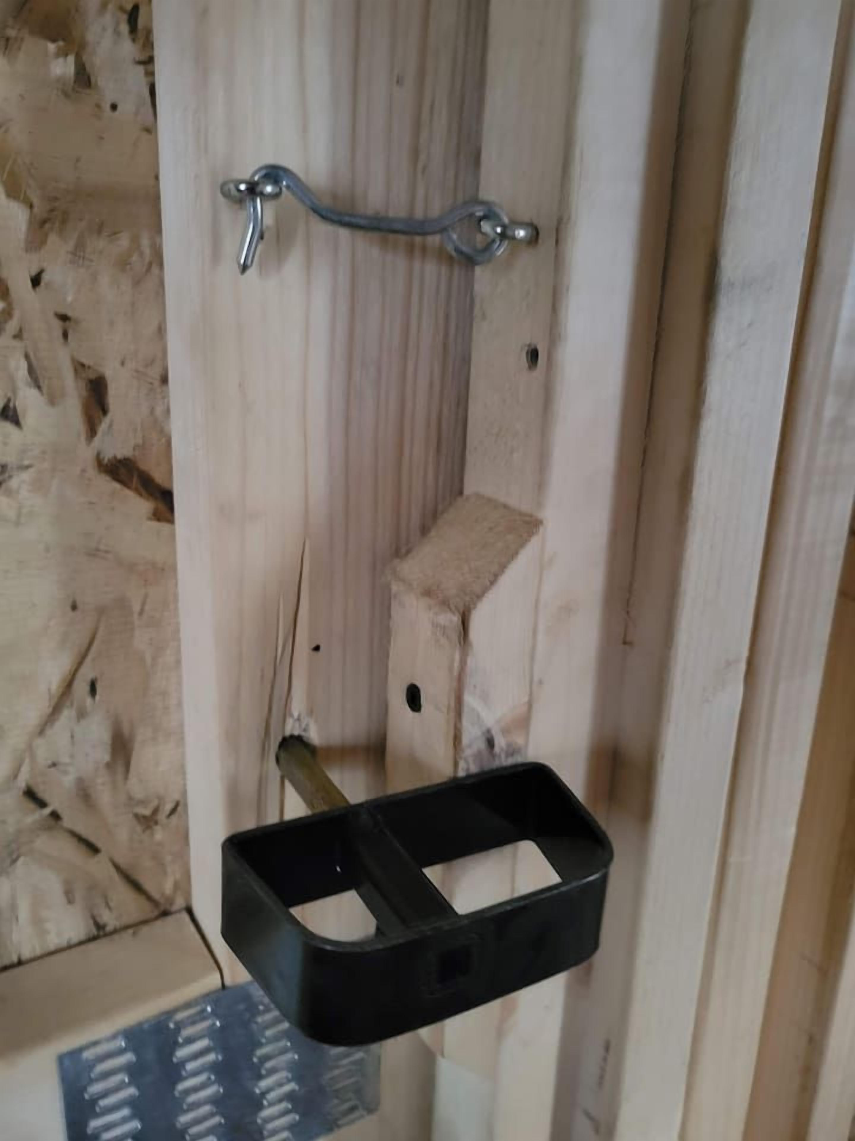 A wooden door with a metal handle and a black object hanging on it.