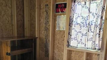 Ein Zimmer mit einem Etagenbett, einem Fenster mit floralem Vorhang und einem Rauchverbot-Schild.