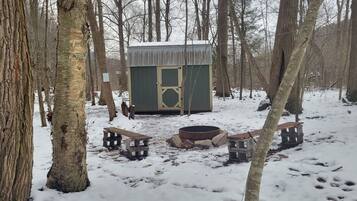 Una baita con un focolare e panche in una foresta innevata.