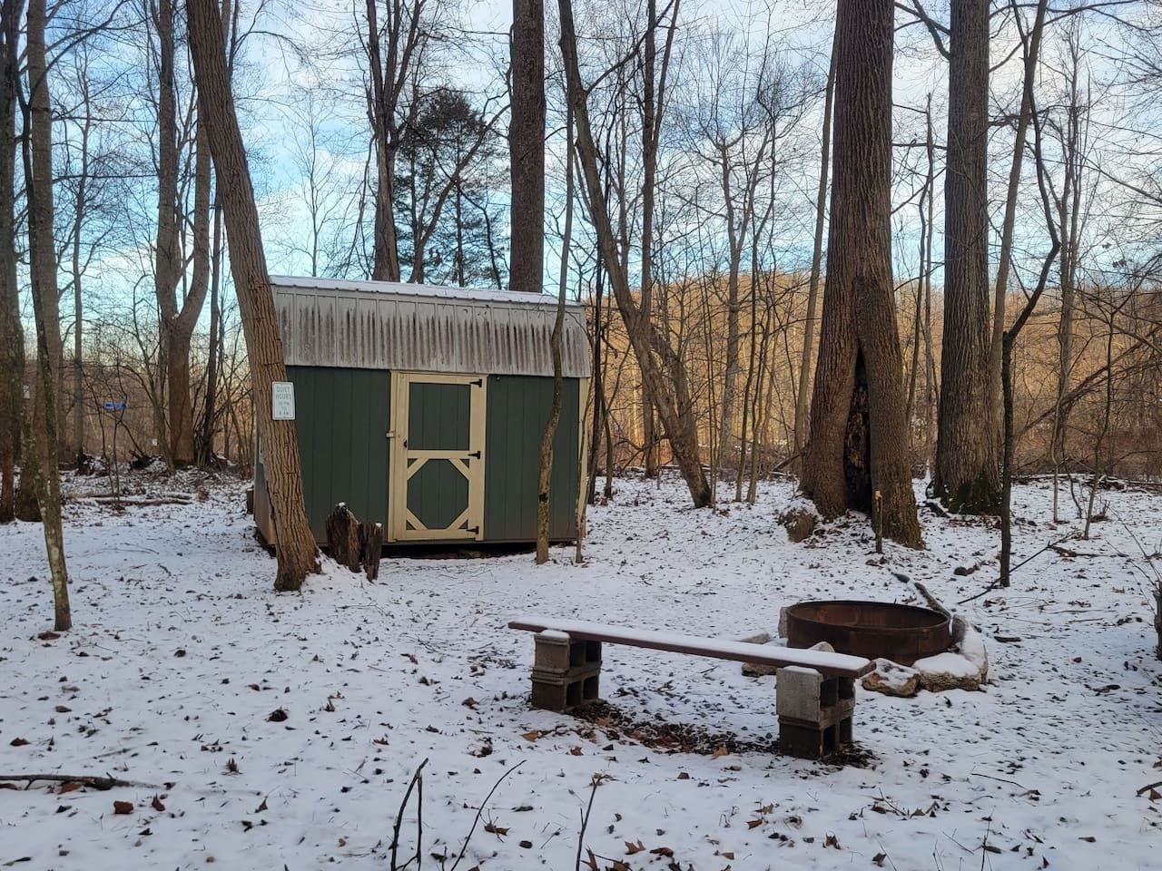 A cabin with a snow-covered ground, surrounded by trees.