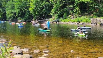 Ein Fluss mit klarem Wasser, umgeben von Felsen und Grün.