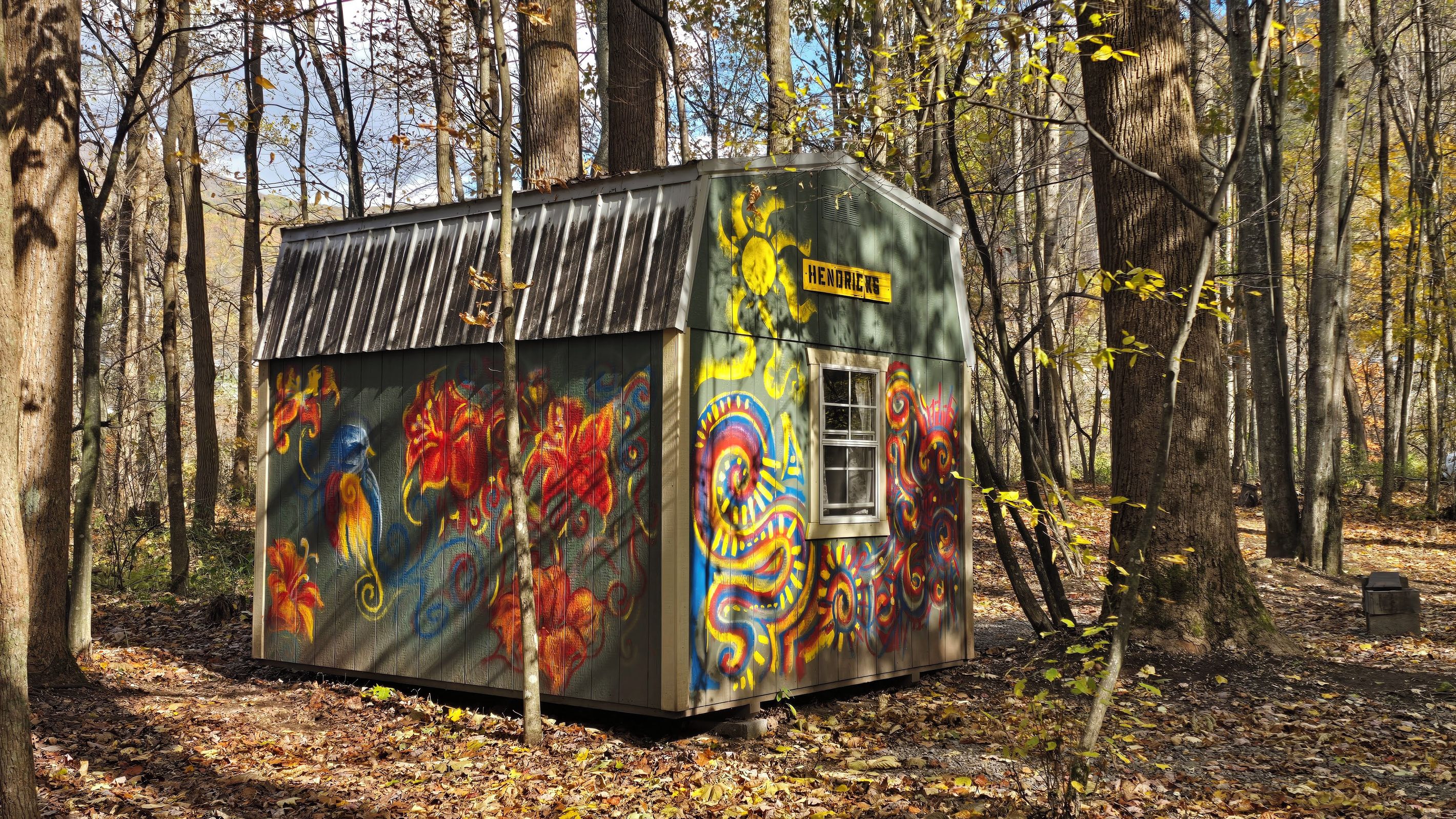 Un piccolo chalet rustico con graffiti colorati, immerso in una foresta.
