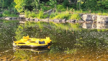 A yellow inflatable raft on a calm river surrounded by rocks and greenery.