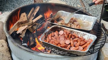 A portable grill with sausages cooking over an open flame.