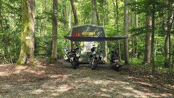 A small cabin with a sign reading 'ROSENDORFF' in a forested area with two motorcycles parked in front.